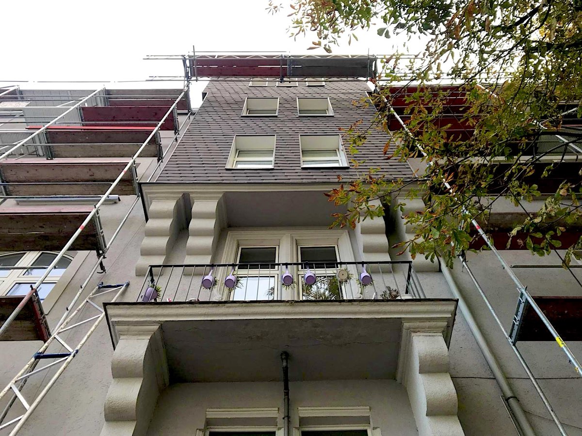 Altbau mit Stuckfassade und Balkon zwischen Gerüsten